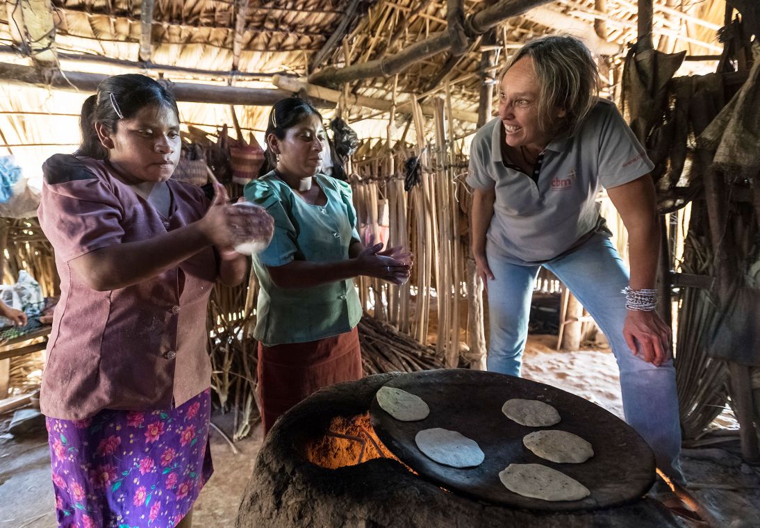Eine CBM-Beraterin sieht stolz zu, wie zwei blinde Frauen in ihrer Hütte in Guatemala völlig selbständig Tortillas backen-