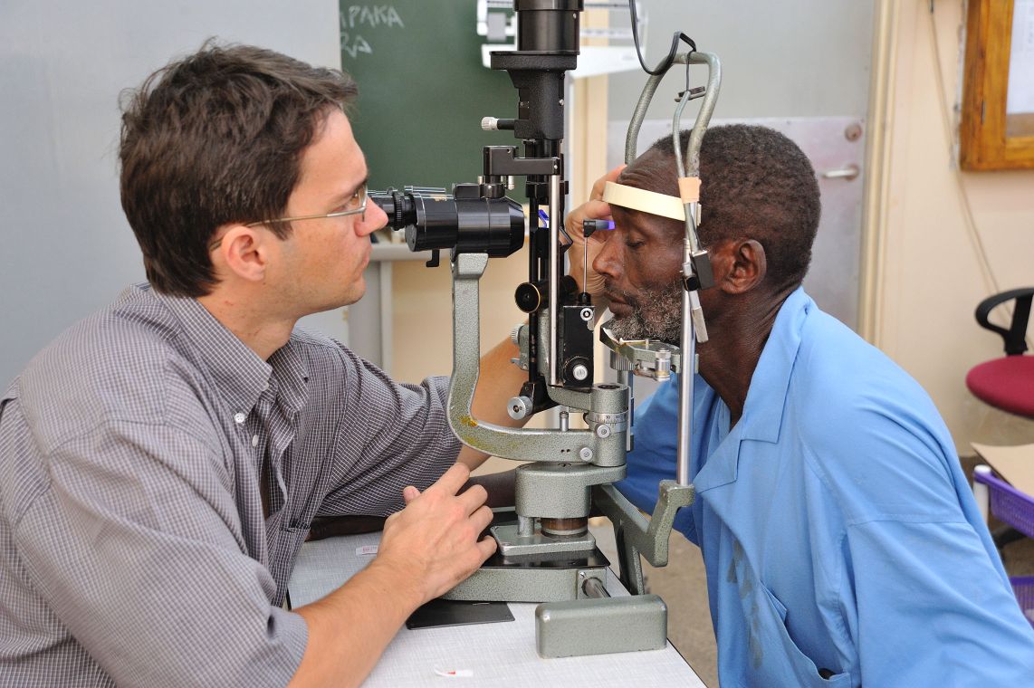 Augenarzt Dr. Heiko Philippin untersucht einen älteren Mann an den Augen.