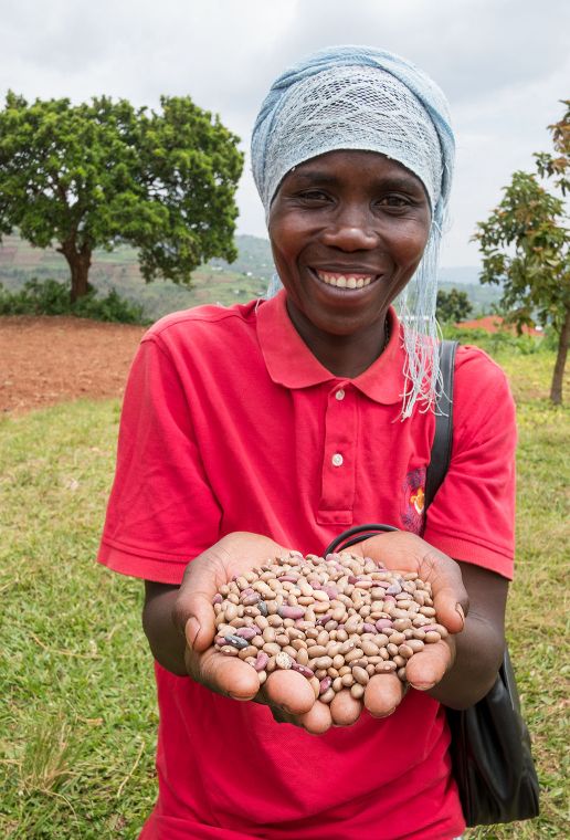 Afrikanische Frau hält lächelnd Bohnen in ihren Händen.