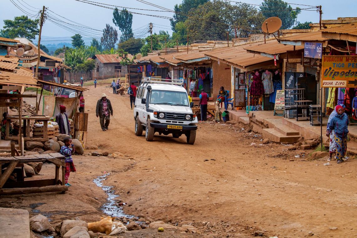 Ein Jeep fährt durch ein afrikanisches Dorf.